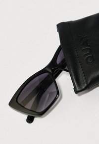 Czarne okulary przeciwsłoneczne z geometryczną oprawką i gradientowymi szkłami, w zestawie z teksturowanym czarnym skórzanym etui z tłoczonym napisem "QUAY".