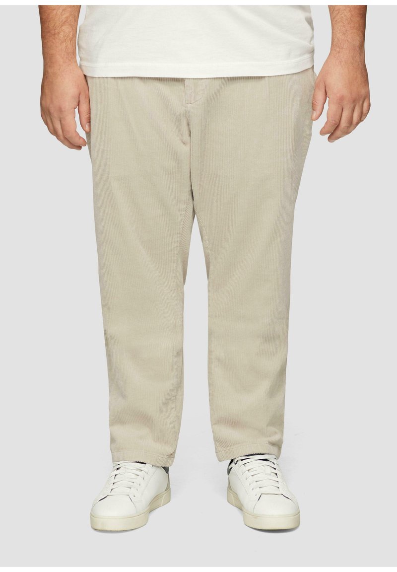 Beige corduroy broek met een rechte snit, voorzien van subtiele verticale strepen, gecombineerd met witte sneakers. Losse pasvorm met een soepele textuur.