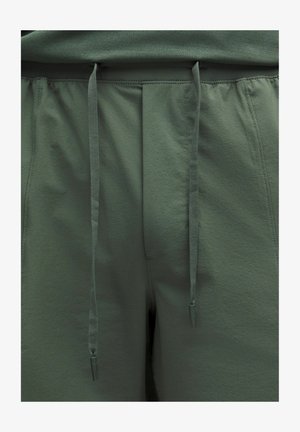 Szürkészöld sportnadrág texturált felülettel, rugalmas derékrésszel és műanyag végekkel ellátott zsinórral.