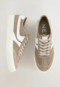 Beige ruskind sneakers med hvide læderdetaljer. Funktioner inkluderer runde snørebånd, en tekstureret gummisål og et syet design på overdelen.