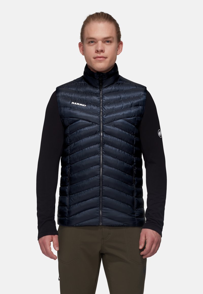 Mit Wattierung, ärmellose Weste in Dunkelblau mit hohem Kragen, mit Zickzack-Nähten und einem Logo auf der linken Seite. Leichter Stoff.