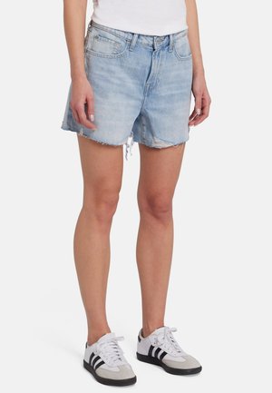 Shorts en jean bleu clair avec un ourlet effiloché, design à cinq poches et coupe décontractée. Associés à des baskets gris et blanc avec des rayures noires.