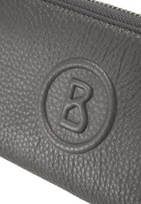 Šedé kožené pouzdro s texturovaným povrchem, zdobené kruhovým raženým logem s písmenem "B" uprostřed a zipovým uzávěrem nahoře.