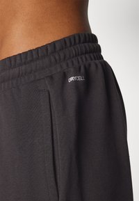 Black athletic pants made of soft fabric, featuring an elastic waistband and side pockets. "DRYCELL" logo is visible on the left side.