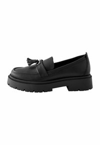 Black leather loafer with a glossy finish, featuring a tassel accent and a thick, textured rubber sole for added grip.