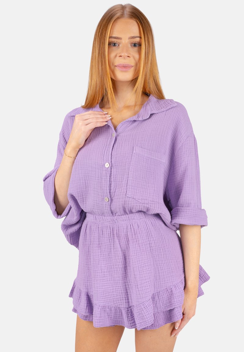Lila Baumwolle-Loungewear-Set mit einem knöpfbaren Oberteil mit Tasche und einem Rüschensrock mit elastischem Taillenbund. Strukturierter, atmungsaktiver Stoff.