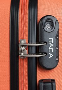 Maleta naranja con un exterior texturizado, cremallera negra y mecanismo de bloqueo plateado brillante. Logo de la marca notable: "ITACA."