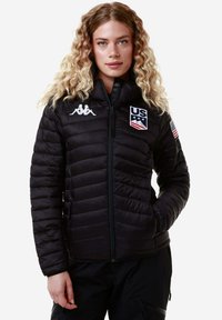 Giacca a vento nera con design trapuntato, caratterizzata dal logo Kappa e dall'emblema della squadra statunitense. Chiusura con zip completa, texture morbida e maniche inserite.