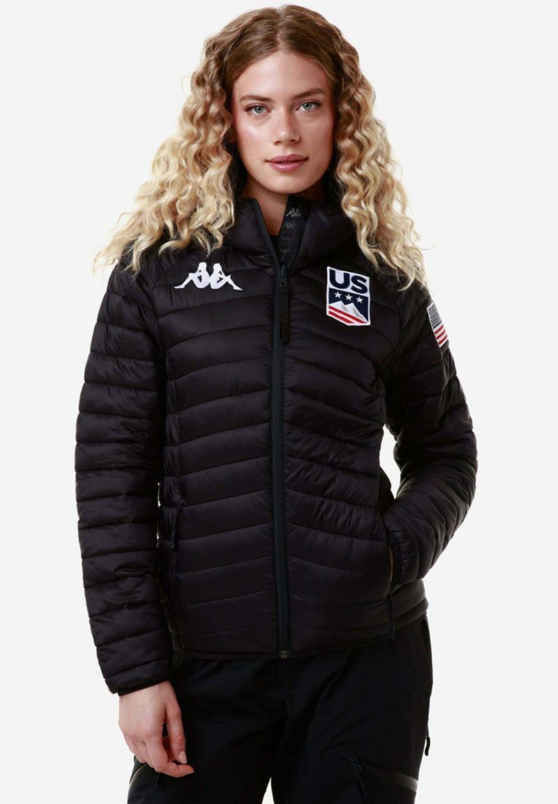 Giacca a vento nera con design trapuntato, caratterizzata dal logo Kappa e dall'emblema della squadra statunitense. Chiusura con zip completa, texture morbida e maniche inserite.