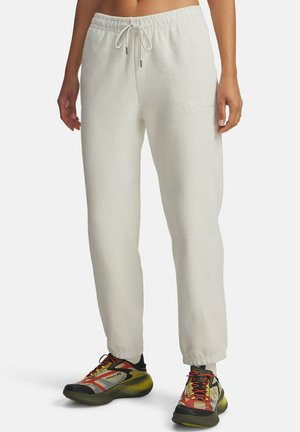Donna che indossa pantaloni felpati off-white con texture e una cintura con cordino, abbinati a scarpe sportive multicolori con dettagli neri, gialli e rossi.