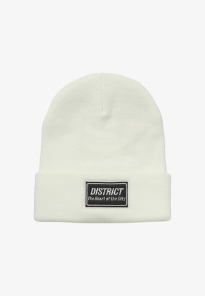Beanie lavorato a maglia di colore crema con risvolto, caratterizzato da un'etichetta nera rettangolare con testo bianco. Texture liscia, design semplice.