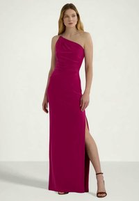 Φούξια φόρεμα one-shoulder με πλαϊνό σκίσιμο, κατασκευασμένο από μαλακό ύφασμα με ελαφριά πτύχωση, διαθέτοντας μια διακριτική λεπτομέρεια στον ώμο.