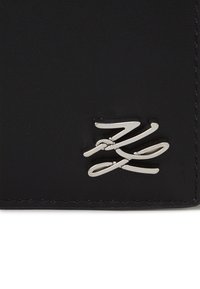 Portefeuille en cuir noir avec un accent en métal argenté poli, texture lisse et bords cousus pour plus de durabilité. Forme rectangulaire compacte.