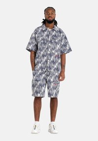 Korte mouwen knoopshirt en bijpassende cargoshorts in een blauw-wit abstract patroon, gemaakt van lichte stof en voorzien van zakken.