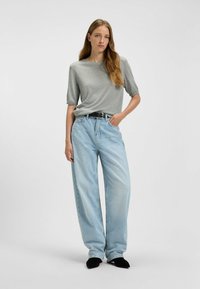 Gray short-sleeve top paired with high-waisted, light blue wide-leg jeans. Black belt and black shoes complete the outfit.