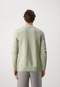 Ljusgrön tröja i ribbad textur, långärmad och med rund halsringning, med ribbad nederkant och ärmslut. Slät tygfinish.