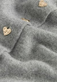 Tessuto grigio texturizzato con una sensazione morbida, caratterizzato da brillanti accenti a forma di cuore dorato cuciti sulla superficie.