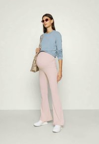 Conjunto de maternidade com uma blusa de mangas longas azul clara, calças flare rosa pálido, ténis brancos e uma bolsa de padrão de leopardo.