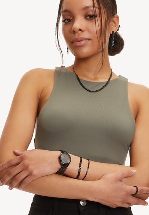 Haut sans manches olive, texture lisse, design ajusté. Accessoires : montre noire, deux bracelets en chaîne et collier assorti. Pas de motifs visibles.