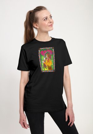 Jeune femme avec une longue queue de cheval portant un t-shirt noir avec un motif psychédélique coloré de Pink Floyd avec une bordure fleurie.
