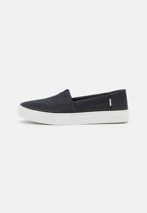 Chaussures à enfiler en tissu gris foncé, avec une texture lisse, une semelle en caoutchouc blanche et des détails de couture minimaux sur la tige.