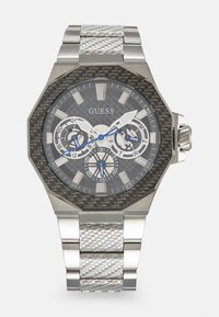 Reloj octagonal para hombre con un dial texturizado en gris, caja de acero inoxidable, acentos azules y una pulsera de metal trenzado.