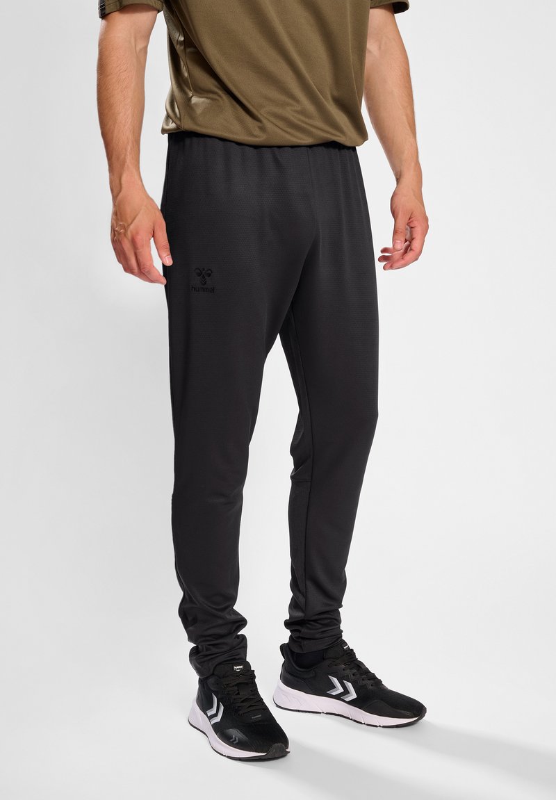 Schwarze Sporthose aus weichem Material, mit elastischem Bund und Taschen an den Seiten. Enthält ein dezentes Markenlogo am Oberschenkel.