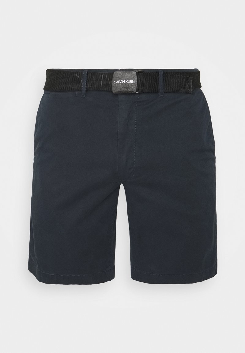 Pantaloni corti blu navy con una texture liscia, dotati di una vita brandizzata nera e tasche frontali. Design a gamba dritta con orli cuciti.