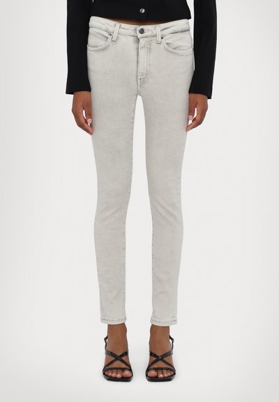Lys grå skinny jeans med et klassisk fem-lomme design, lynlås lukning og tonalt syning. Sammen med sorte strophæle.