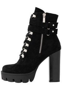 Stivaletto in suede nero con tacco chunky, lacci frontali con occhielli in metallo argentato, chiusura laterale con zip e suola spessa a contrasto con scanalature.