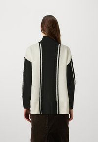 Cardigan lavorato a maglia con colletto alto, caratterizzato da righe bianche e nere, polsini a costine e motivi testurizzati sul retro.