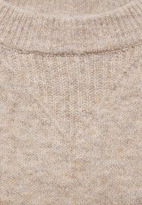 Beżowy sweter dzianinowy z teksturowanym wzorem, z prążkowanym kołnierzem i detalem w kształcie litery V przy dekolcie. Ciepły, miękki materiał wełniany.