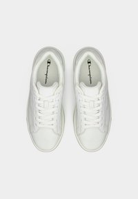 Άσπρα χαμηλά παπούτσια Champion με κορδόνια, ορατό λογότυπο στο εσωτερικό και καθαρό μινιμαλιστικό σχέδιο σε απλό φόντο.