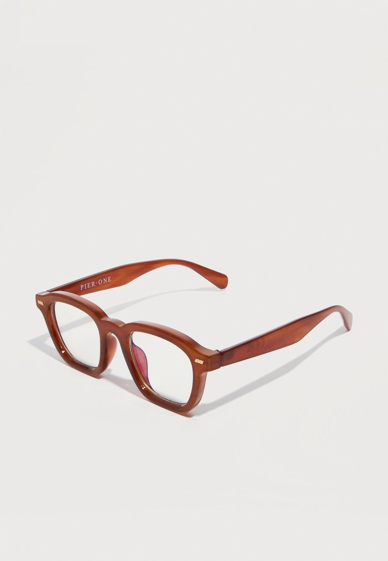 Καφέ διαφανή ορθογώνια γυαλιά με παχιά πλαίσια που είναι επίπεδα τοποθετημένα σε λευκή επιφάνεια, με την ένδειξη "Pier One" στο μπράτσο.