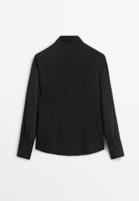 Chemise de soirée noire à manches longues avec poignets boutonnés, vue de dos sur un fond gris clair.