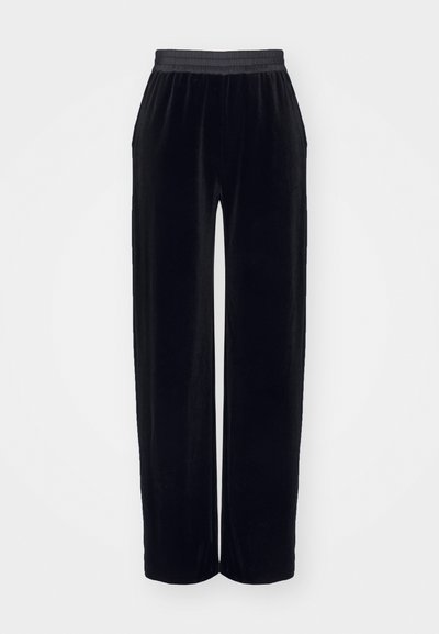 Pantaloni din catifea neagră cu un brâu elastic, având un design cu picioare largi și o textură netedă, moale. Fără modele vizibile sau accesorii metalice.
