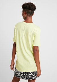 Koszulka z krótkim rękawem w jasnym żółtym kolorze, okrągły dekolt, miękka bawełniana faktura, w połączeniu z spódnicą w czarno-białą panterkę.