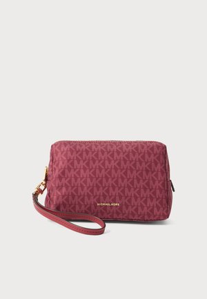 Малка розова гривна Michael Kors с повтарящ се модел на логото MK и златен цип на бял фон.