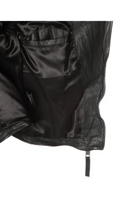 Veste en cuir noire partiellement ouverte pour montrer la doublure intérieure lisse et une poche intérieure sur le côté gauche.