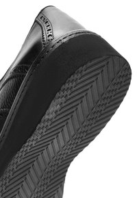 Schwarzer Lederschuh mit strukturierten Akzenten, Nahaufnahme der konturierten Gummisohle mit einem Profilmuster für besseren Halt.