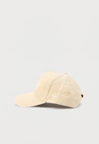 Beež värvi korduroost nokamüts kõverdatud nokaga, esiküljel tikitud logo, silmadega ventilatsiooniaugud ja taga reguleeritav rihm.