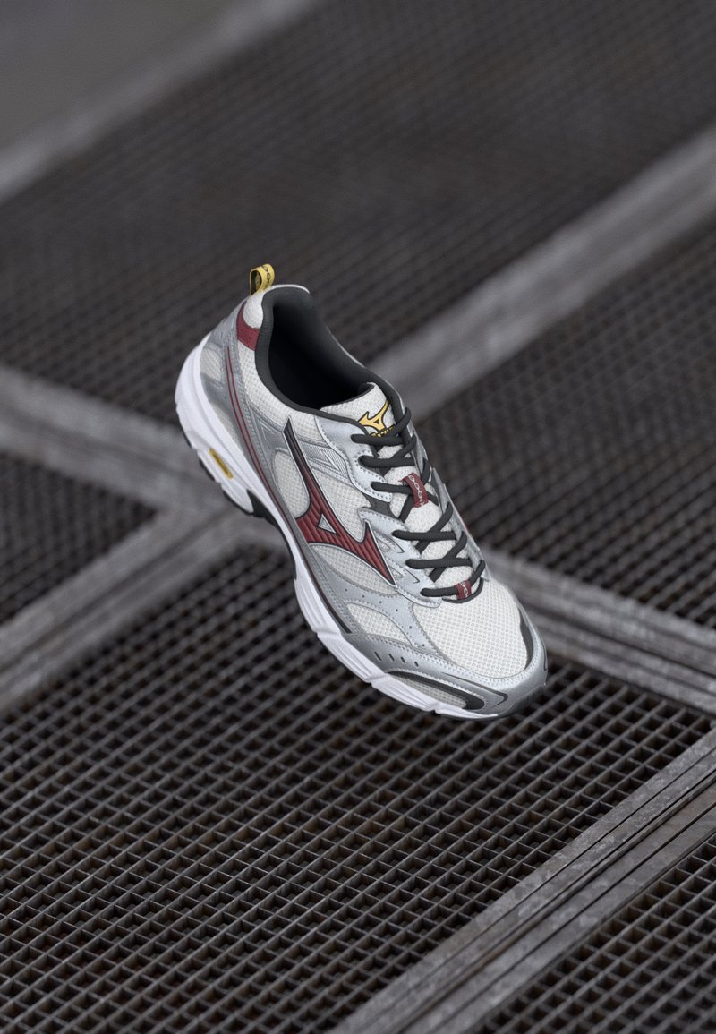 White and silver lace-up sneaker with red accents, mesh upper, padded collar, and rubber outsole, featuring a textured pattern and logo detail.