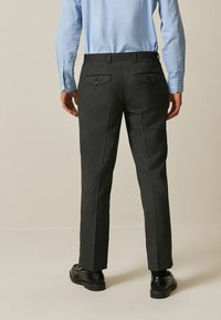 Dark gray striped trousers with a tailored fit, featuring two back pockets and button closures. Paired with black shoes.