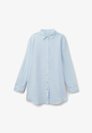 Camisa azul claro de manga larga con botones, cuello puntiagudo y sutil patrón de rayas verticales texturizadas.