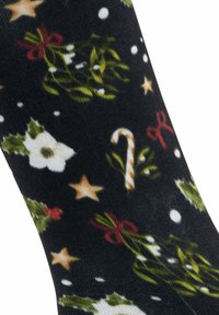 Czarne skarpetki z motywem świątecznym, na których znajdują się białe kwiaty, zielone liście, czerwone kokardy, cukrowe laski, gwiazdy i białe kropki.