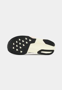 Shoe sole featuring a black rubber base with a textured pattern and triangular cutouts, contrasted by a white midsole and red accent.