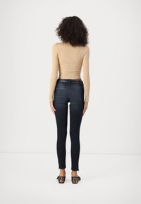 Ribbed beige cropped sweater paired with dark denim skinny jeans featuring back pockets. Worn with leopard print low-heeled shoes.
