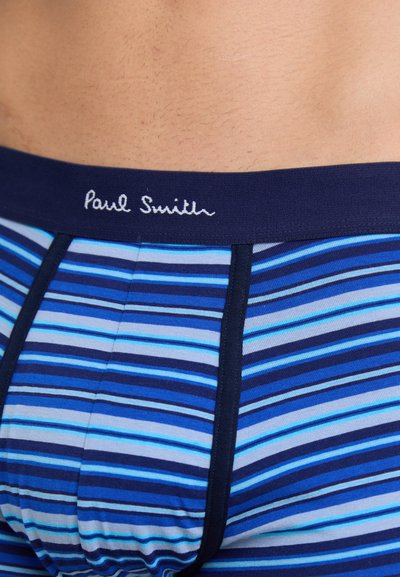 Kék és sötétkék csíkos férfi boxeralsó, kontrasztos derékszíjjal. A derékszíjon fehér hímzett 'Paul Smith' logó található.