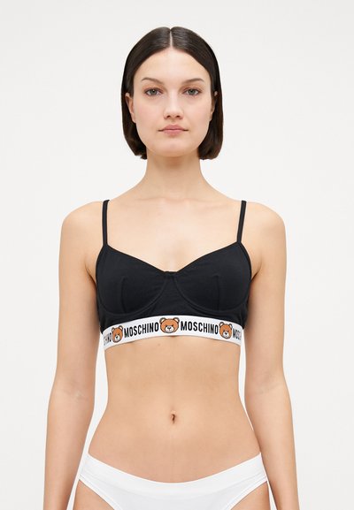 Fekete pamut melltartó, strukturált kialakítással, állítható pántokkal és egy fehér elasztikus szalaggal, amelyen medve minta és a "Moschino" logo található.