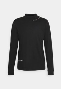 Svart långärmad tröja med hög krage som har texten "Tommy Hilfiger" och logotypen nära kragen samt texten "New York, Est. 1985" nära sömmen.